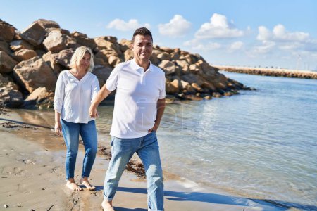 Téléchargez les photos : Middle age man and woman couple smiling confident walking at seaside - en image libre de droit