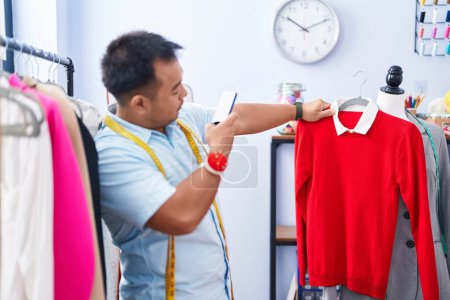 Photo for Young chinese man tailor make photo by smartphone to t shirt at tailor shop - Royalty Free Image