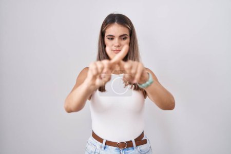 Téléchargez les photos : Hispanic young woman standing over white background rejection expression crossing fingers doing negative sign - en image libre de droit