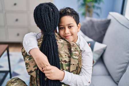 Téléchargez les photos : African american mother and son wearing soldier uniform hugging each other at home - en image libre de droit