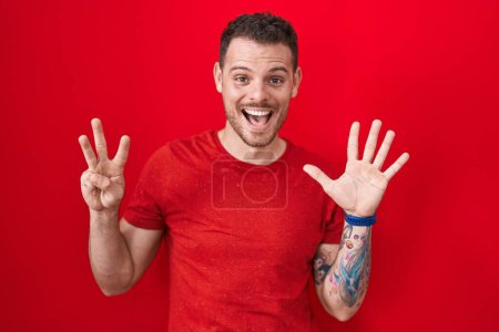 Photo for Young hispanic man standing over red background showing and pointing up with fingers number eight while smiling confident and happy. - Royalty Free Image