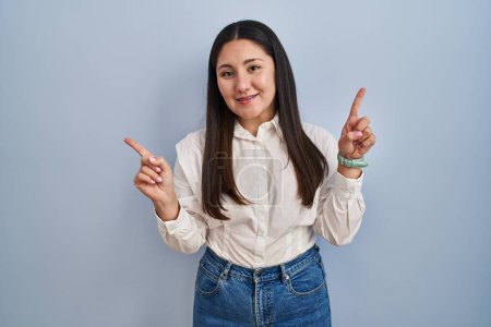 Téléchargez les photos : Jeune femme latine debout sur fond bleu souriant confiant pointant avec les doigts vers différentes directions. espace de copie pour la publicité - en image libre de droit