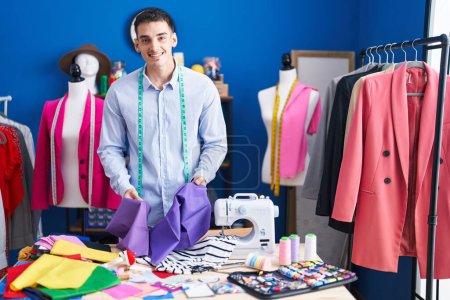 Photo for Young hispanic man tailor smiling confident holding cloth at sewing studio - Royalty Free Image