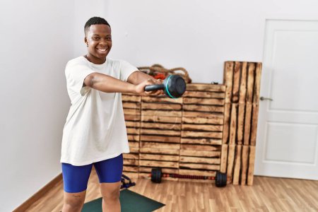 Téléchargez les photos : Jeune homme africain s'entraînant avec des haltères à la salle de gym - en image libre de droit