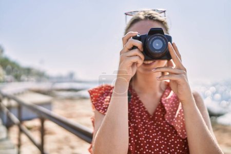 Photo for Young blonde girl smiling happy using camera at the beach - Royalty Free Image