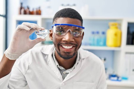 Photo for Young african american man wearing scientist uniform holding diamond at laboratory - Royalty Free Image