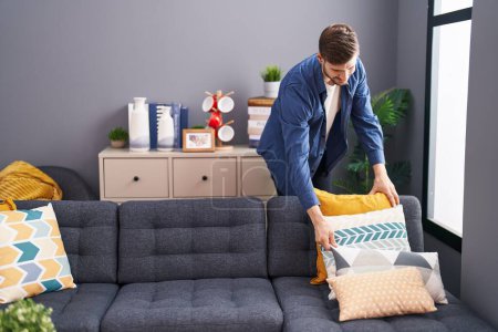 Photo for Young caucasian man smiling confident organize sofa at home - Royalty Free Image