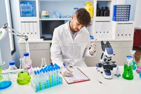 Photo for Young arab man scientist write on document analysing blood test tube at laboratory - Royalty Free Image