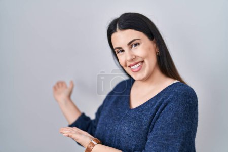 Téléchargez les photos : Jeune femme brune debout sur fond isolé invitant à entrer souriant naturel avec la main ouverte - en image libre de droit