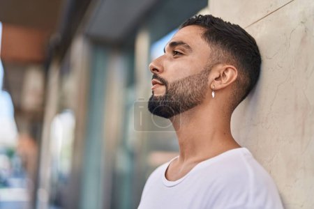 Téléchargez les photos : Jeune homme arabe regardant vers le côté avec une expression sérieuse à la rue - en image libre de droit
