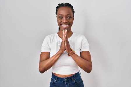 Téléchargez les photos : Beautiful black woman standing over isolated background praying with hands together asking for forgiveness smiling confident. - en image libre de droit
