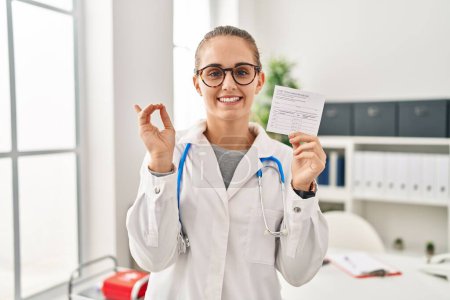 Téléchargez les photos : Jeune médecin femme tenant certificat covide souriant heureux pointant avec la main et le doigt sur le côté - en image libre de droit
