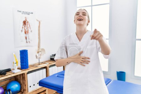 Photo for Young caucasian woman working at pain recovery clinic laughing at you, pointing finger to the camera with hand over body, shame expression - Royalty Free Image