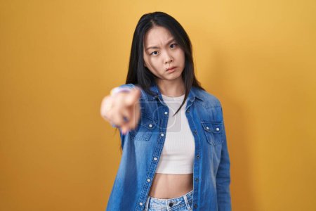 Photo for Young asian woman standing over yellow background pointing displeased and frustrated to the camera, angry and furious with you - Royalty Free Image