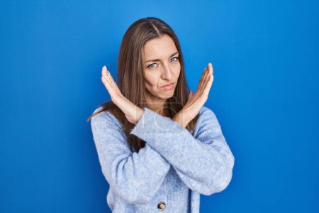 Téléchargez les photos : Young woman standing over blue background rejection expression crossing arms doing negative sign, angry face - en image libre de droit