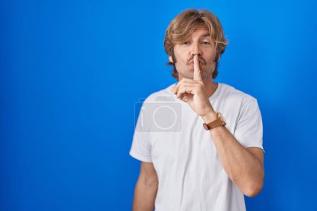 Photo for Middle age man standing over blue background asking to be quiet with finger on lips. silence and secret concept. - Royalty Free Image