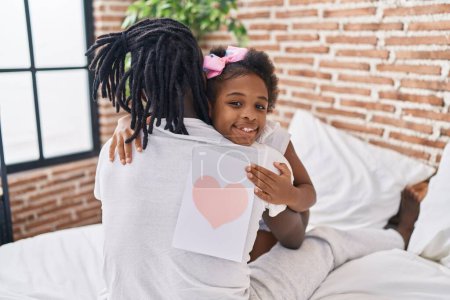 Foto de Padre e hija abrazándose mutuamente sosteniendo un precioso regalo en el dormitorio - Imagen libre de derechos