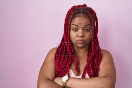 Téléchargez les photos : Femme afro-américaine avec les cheveux tressés debout sur fond rose sceptique et nerveux, expression désapprobatrice sur le visage avec les bras croisés. personne négative. - en image libre de droit