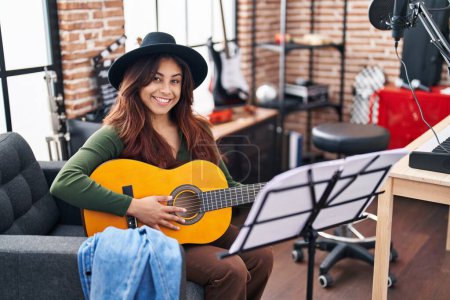 Photo for Young hispanic woman musician playing classical guitar at music studio - Royalty Free Image