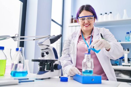Photo for Young beautiful plus size woman scientist pouring liquid on test tube weighing liquid at laboratory - Royalty Free Image