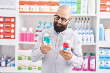 Téléchargez les photos : Young bald man customer smiling confident holding medication bottles at pharmacy - en image libre de droit