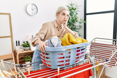 Photo for Young caucasian woman leaning on clothesline at laundry room - Royalty Free Image