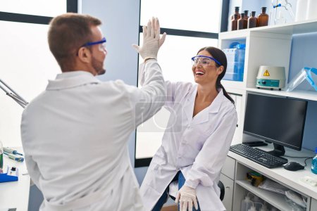 Photo for Man and woman scientist partners high five with hands raised up at laboratory - Royalty Free Image