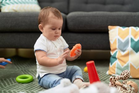 Foto de Adorable niño jugando con juguetes sentados en el suelo en casa - Imagen libre de derechos