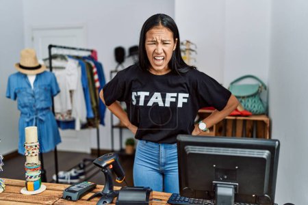 Photo for Young hispanic woman working as staff at retail boutique angry and mad screaming frustrated and furious, shouting with anger. rage and aggressive concept. - Royalty Free Image