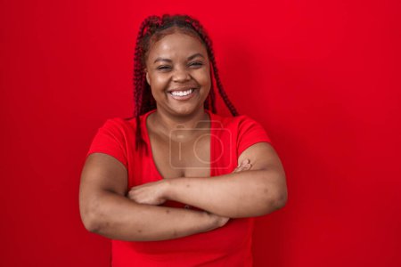 Photo for African american woman with braided hair standing over red background happy face smiling with crossed arms looking at the camera. positive person. - Royalty Free Image