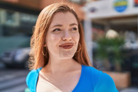 Photo for Young redhead woman smiling confident looking to the side at street - Royalty Free Image