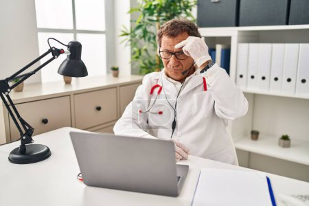 Photo for Senior doctor man working on online appointment pointing unhappy to pimple on forehead, ugly infection of blackhead. acne and skin problem - Royalty Free Image