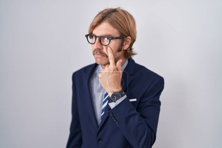Foto de Hombre caucásico con bigote usando ropa de negocios apuntando al ojo observándote gesto, expresión sospechosa - Imagen libre de derechos