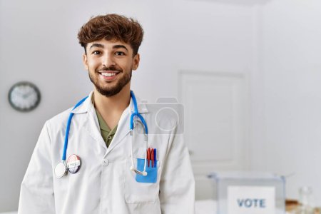 Foto de Young arab man wearing doctor uniform standing at electoral college - Imagen libre de derechos