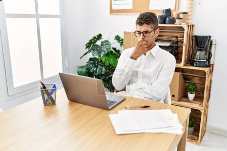 Foto de Joven hombre hispano pensando en trabajar con portátil en la oficina de negocios - Imagen libre de derechos