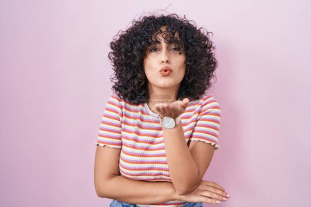 Photo for Young middle east woman standing over pink background looking at the camera blowing a kiss with hand on air being lovely and sexy. love expression. - Royalty Free Image