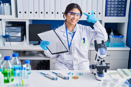Téléchargez les photos : Hispanic young woman working at scientist laboratory smiling pointing to head with one finger, great idea or thought, good memory - en image libre de droit