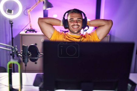 Photo for Young hispanic man streamer smiling confident relaxed with hands head at gaming room - Royalty Free Image