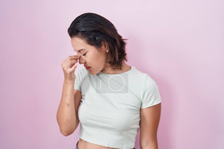Téléchargez les photos : Hispanic young woman standing over pink background tired rubbing nose and eyes feeling fatigue and headache. stress and frustration concept. - en image libre de droit