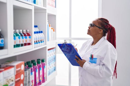 Foto de African american woman pharmacist organize shelving at pharmacy - Imagen libre de derechos