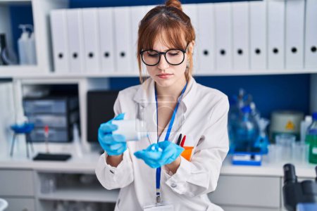 Foto de Mujer joven científica sosteniendo pastillas en el laboratorio - Imagen libre de derechos
