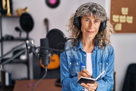 Photo for Middle age woman singer composing song at music studio - Royalty Free Image