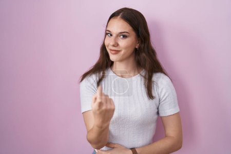 Téléchargez les photos : Young hispanic girl standing over pink background beckoning come here gesture with hand inviting welcoming happy and smiling - en image libre de droit
