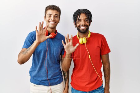 Téléchargez les photos : Young hispanic brothers standing over isolated background wearing headphones showing and pointing up with fingers number ten while smiling confident and happy. - en image libre de droit
