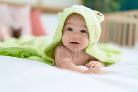 Téléchargez les photos : Adorable tout-petit couché sur le couvercle de lit avec une serviette drôle dans la chambre - en image libre de droit