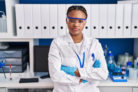 Foto de African american woman scientist standing with arms crossed gesture at laboratory - Imagen libre de derechos