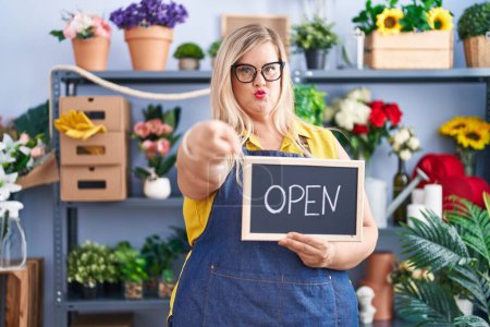 Photo for Caucasian plus size woman working at florist holding open sign pointing with finger to the camera and to you, confident gesture looking serious - Royalty Free Image