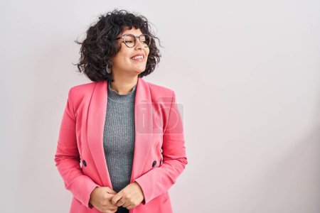 Photo for Hispanic woman with curly hair standing over isolated background looking away to side with smile on face, natural expression. laughing confident. - Royalty Free Image