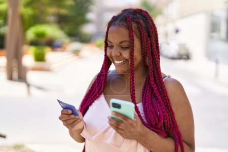 Foto de African american woman using smartphone and credit card at street - Imagen libre de derechos