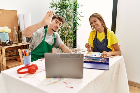 Photo for Young hispanic artist couple smiling happy having online draw lesson at art studio. - Royalty Free Image